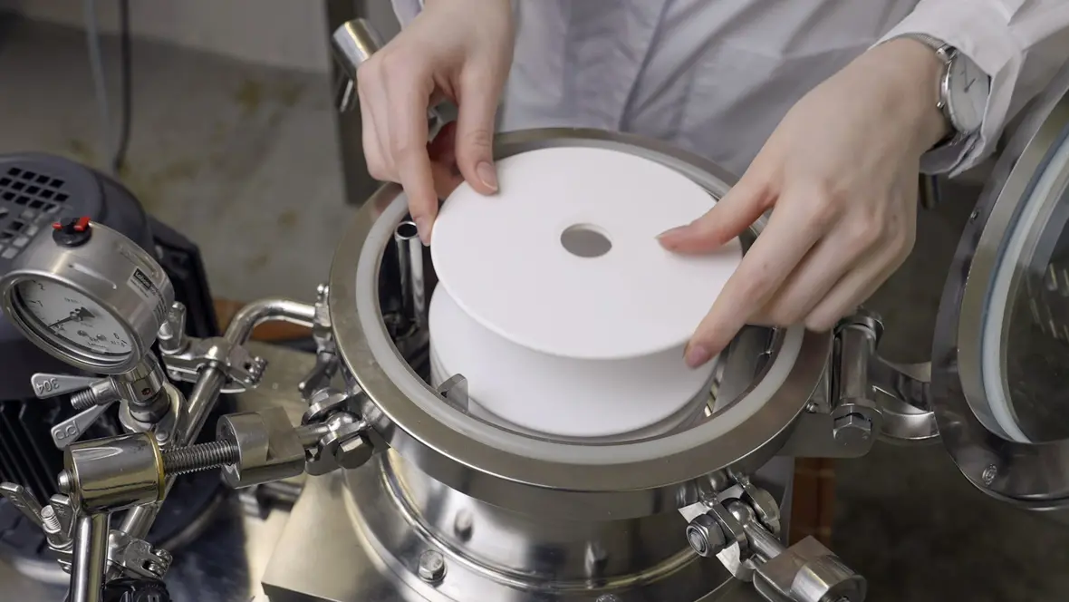 Weißer Keramikfilter Es sind die Hände einer Person zu sehen, die Keramikfilter in eine Maschine einlegt.
